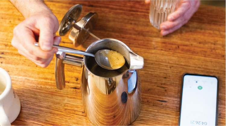 Scooping out some coffee from a French press plunger