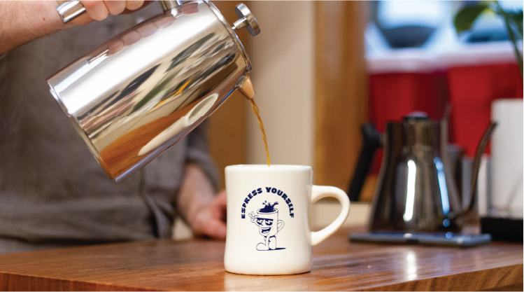 French press plunger pouring coffee into Rumble Coffee diner mug designed by Andy Hoffman