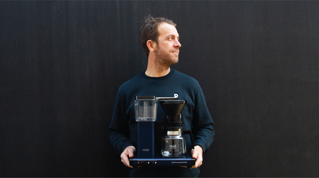 Matt from Rumble Coffee holding a Moccamaster Classic in shade Midnight Blue.