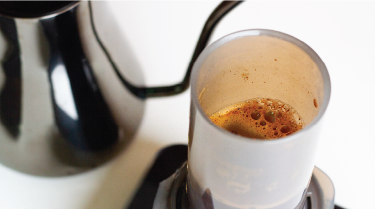 Close up of Aeropress brewing coffee. Stagg kettle in background
