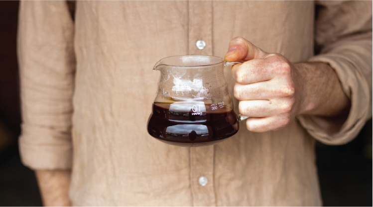 Hand holding carafe of filter coffee, brewed using a Hario v60 filter kit, and Rumble Coffee Roasters single origin coffee.