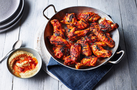 Harissa spiced wings in a silver dish served with a spiced houmous 
