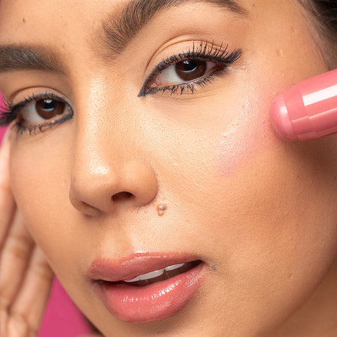 Model applying Palladio's Blush stick to add a natural flush of color to cheeks