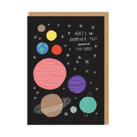 happy birthday card that reads 'here's to another trip around the sun'. the card shows several colourful planets and stars on a black background