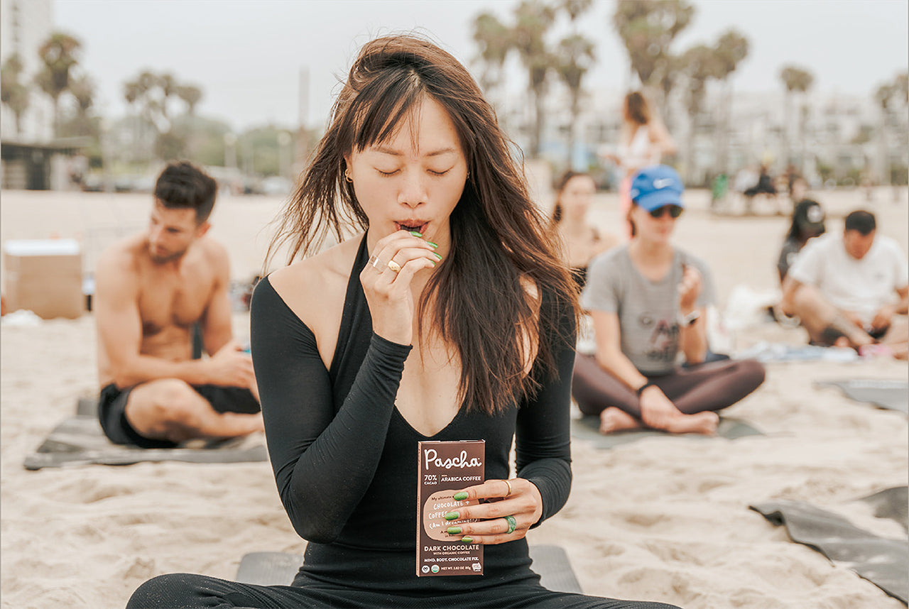 Lady with eyes closed sitting on beach enjoying Pascha Organic Dark Chocolate Bar