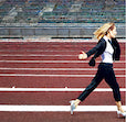 a woman sprinting in a business suite carrying a briefcase on a track