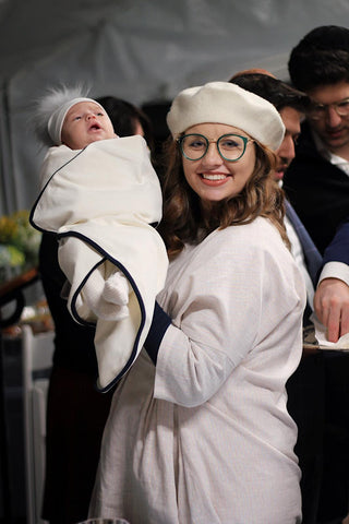 The author holding her first child while wearing The Origami Dress