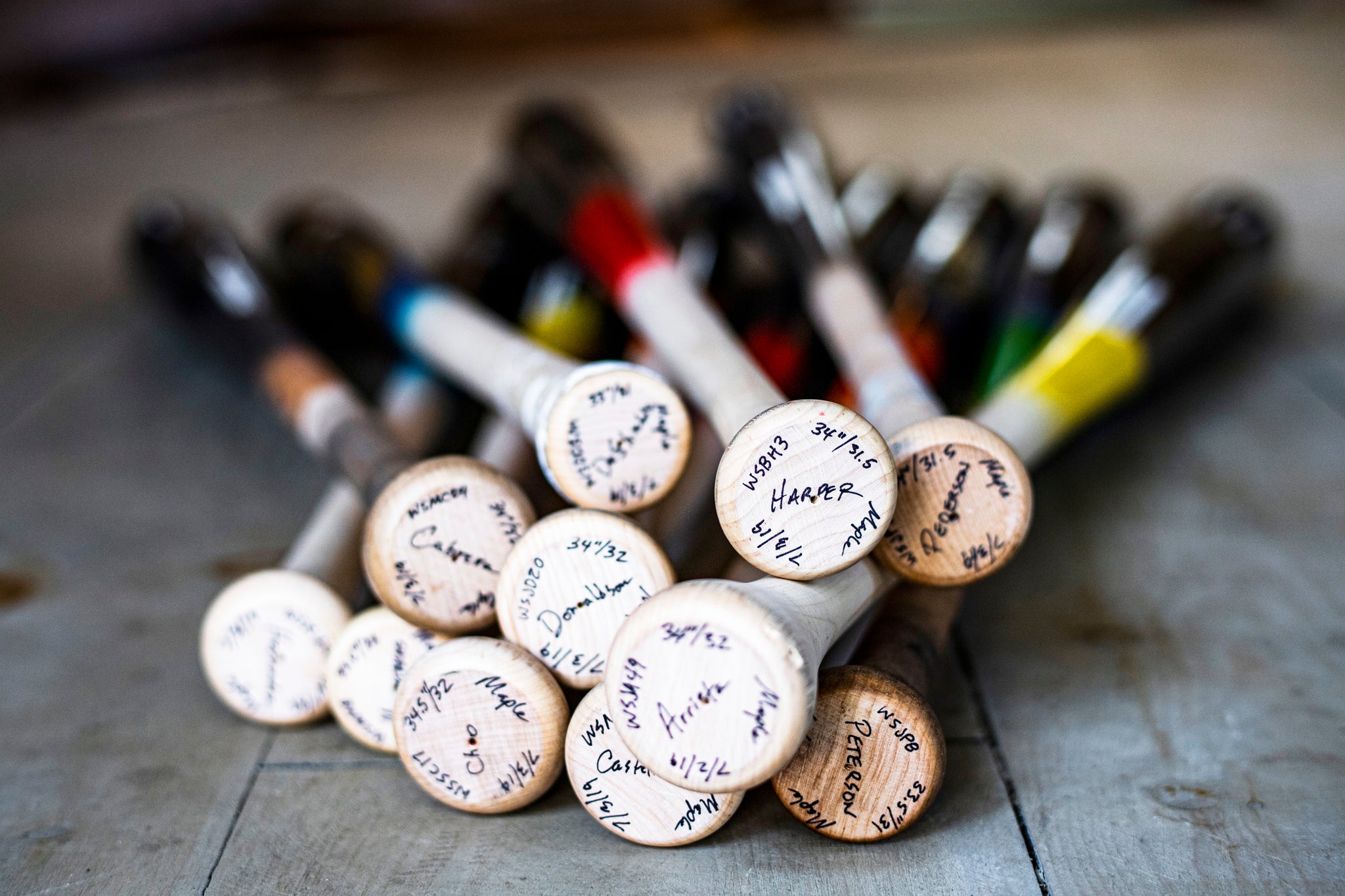 All of the player's weekend bats in a pile, view of their knobs with the player's bat specs on them.