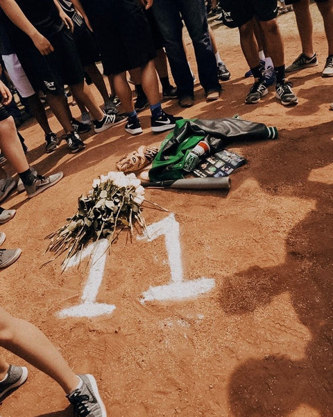 A group of high schoolers gathered around the number 11 written in line chalk on the pitcher's mound.
