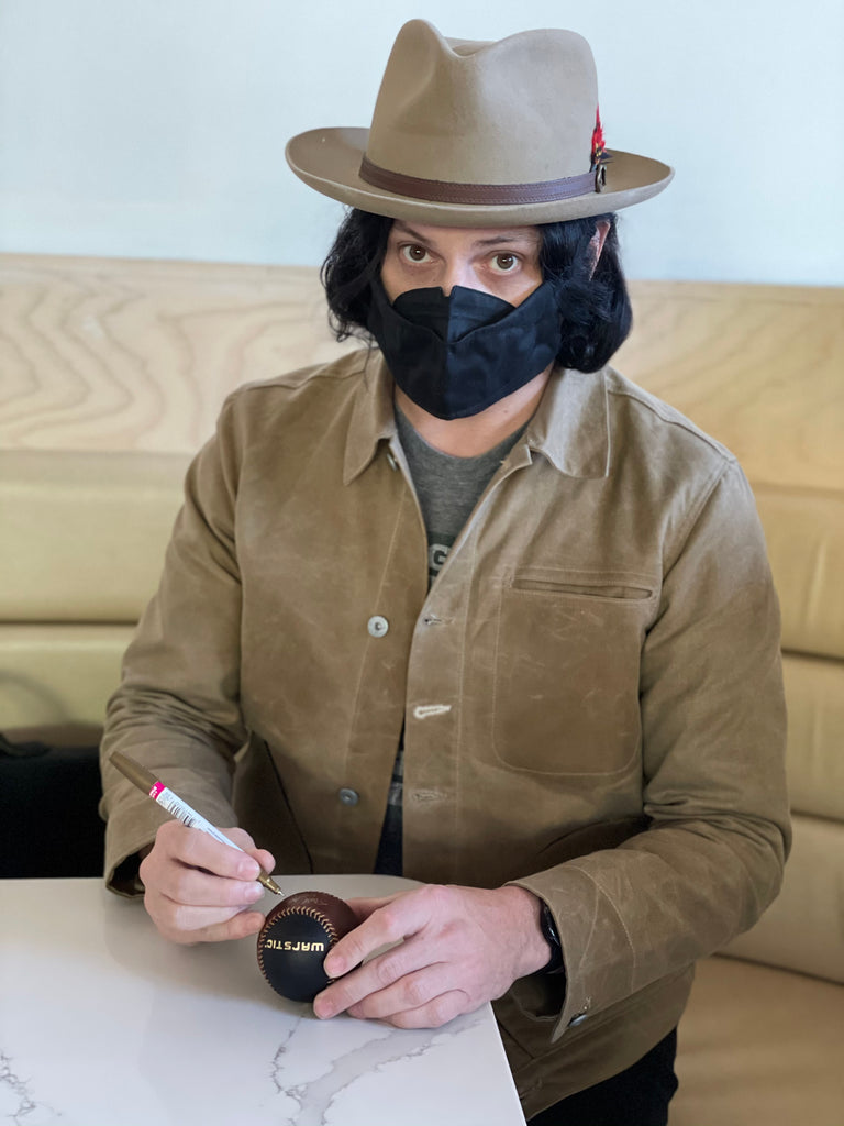 Jack White autographing a baseball.