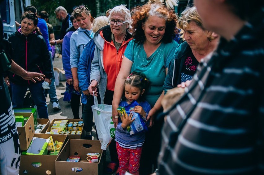 Ukrainians wait in line to get food from aid workers.