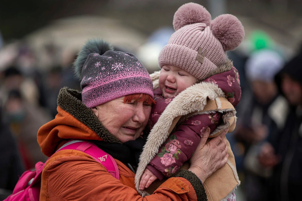 A woman holding a child cries after fleeing from Ukraine and arriving at the border crossing in Medyka, Poland.