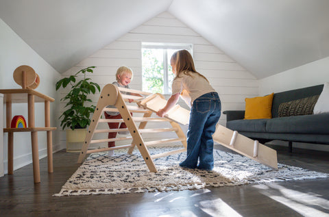 two children using a climbing triangle and ramp to play together