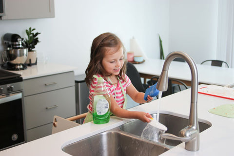 a girl stands at the kitchen sink in a learning tower