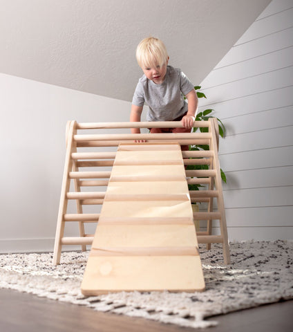 a boy climbs a wooden climbing triangle with ramp