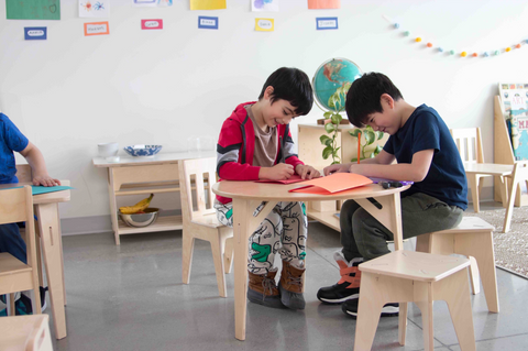 Two students sitting at a desk in a Montessori classroom
