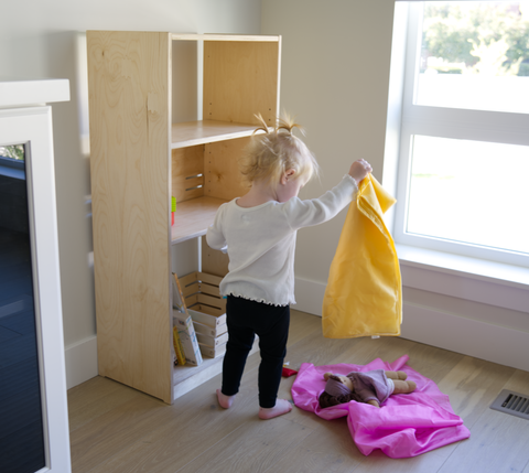 child playing with toys from a shelf