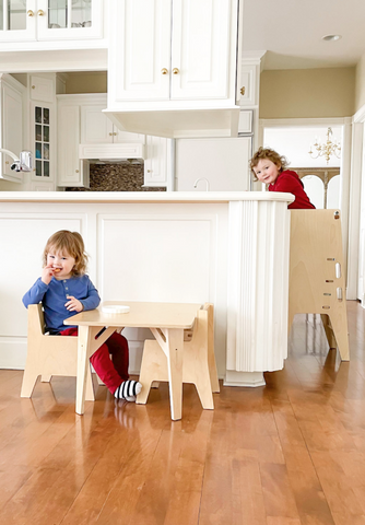 Two children in a kitchen space using Montessori furniture