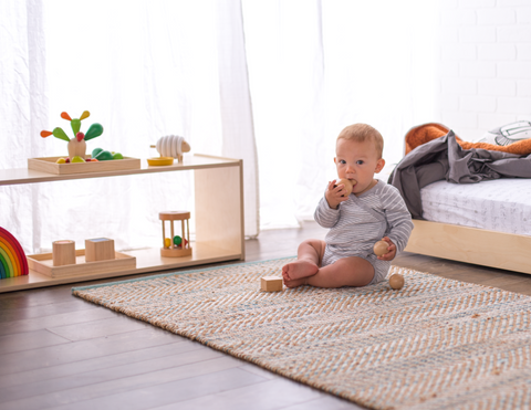 Baby sitting on the floor in front of a toy shelf