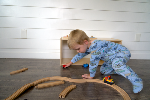 child playing with trains in pajamas