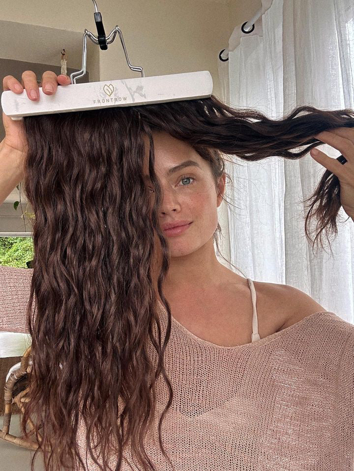 Image of Jess Lee Buchanan holding up her Frontrow clip-in hair extensions attached to the Frontrow storage and styling hanger