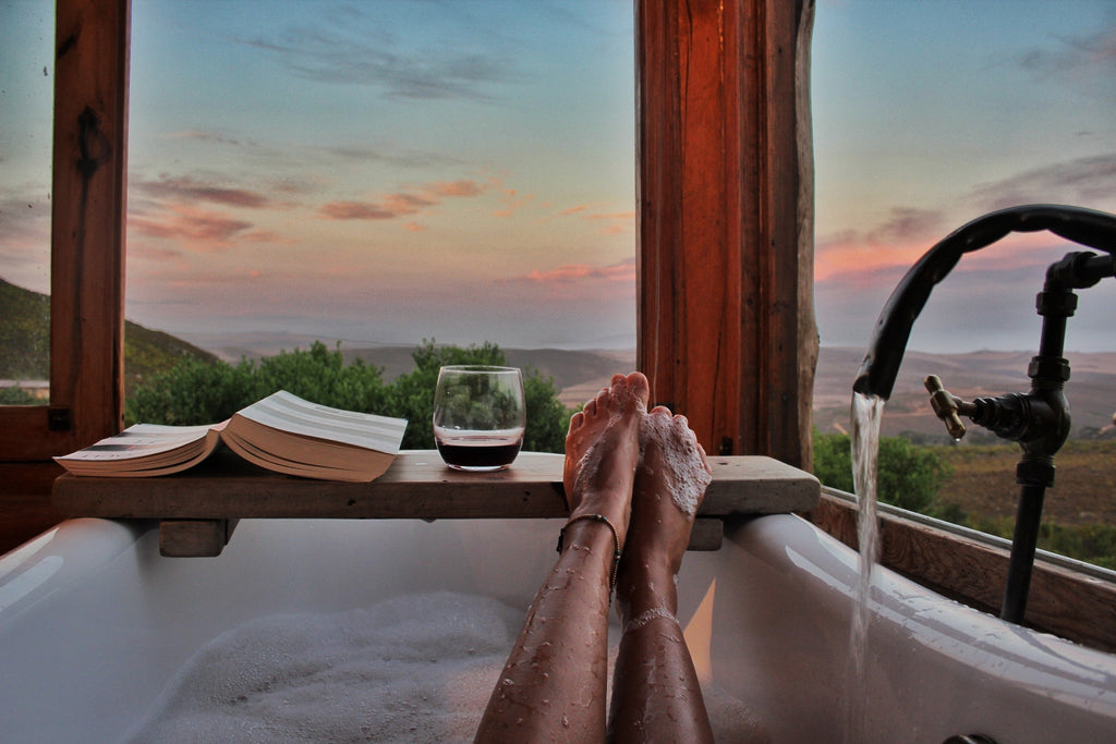 Image of woman in bath with a beautiful sunset view and a book