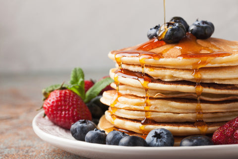 stack of pancakes with syrup and fruit