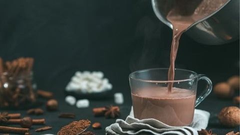 Pouring hot chocolate from a pan to a mug. eat2explore