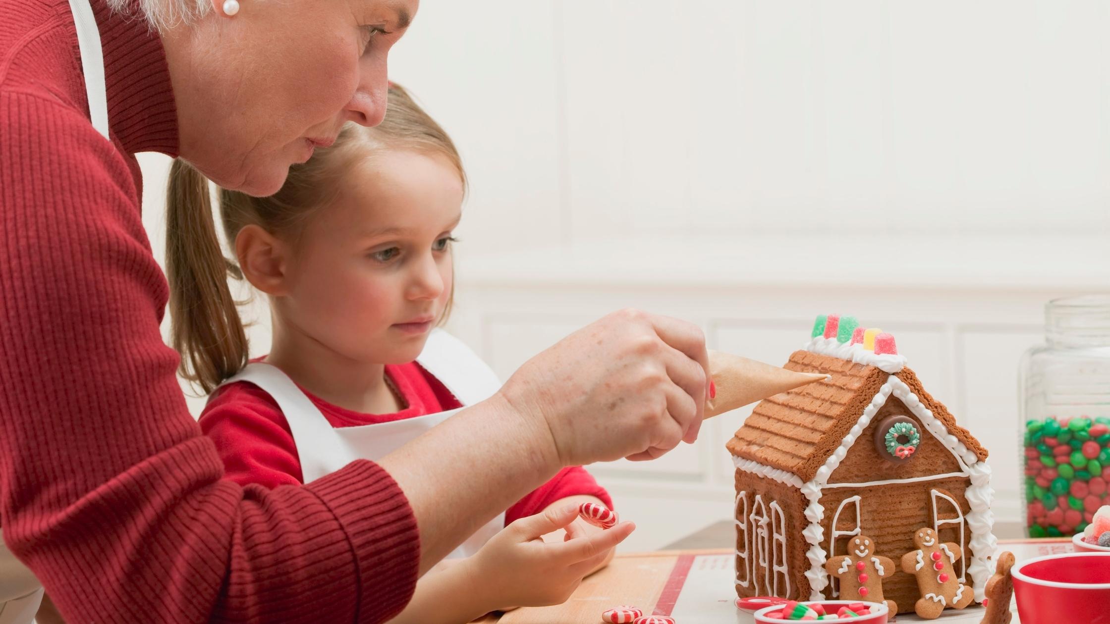 adult and child decorating a gingerbread house