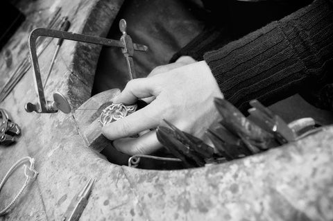 image in black and white of jewellers hands making a necklace at the workbench