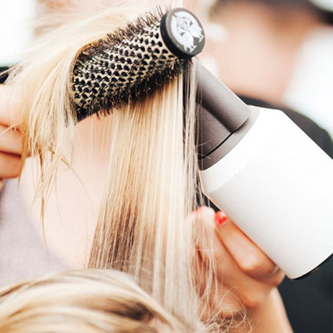 Women blow drying her hair with round brush machine