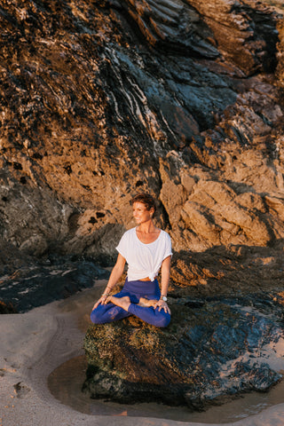 Woman sitting on the rock in a yogic posture