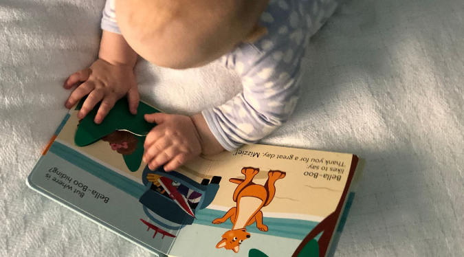 Baby reading 'At The Beach' book
