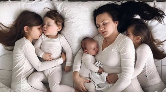 Mom sleeping with her 4 kids after a big day