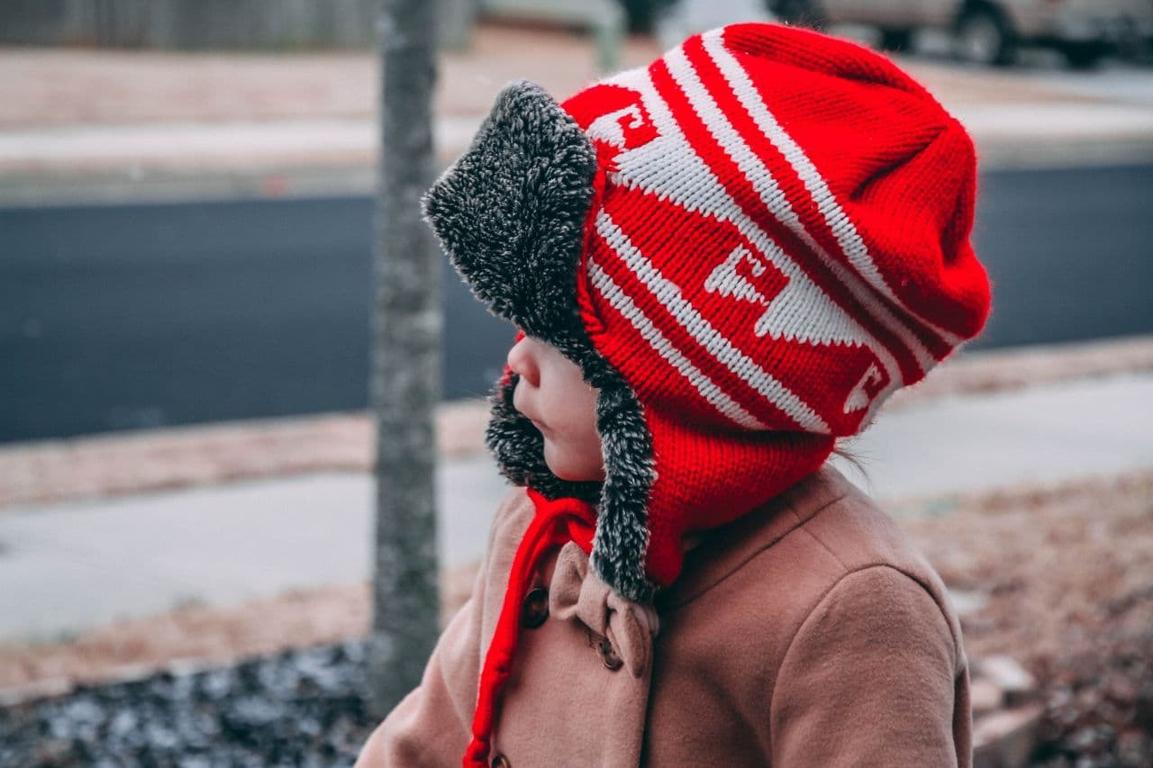 A toddler wearing a winter coat and hat.
