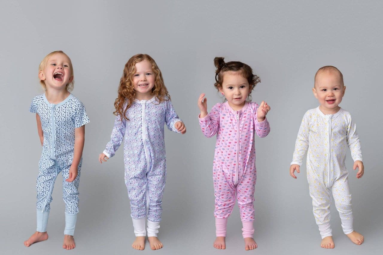 Toddlers dressed in long-sleeve zip-up bodysuits.