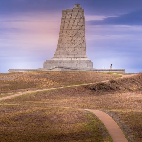 monument on the hill with blue skies and walking path