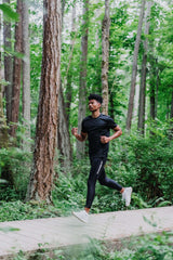 A vertical shot of a runner on a path with green grass and trees. Running with IT band, it band pain running, knee braces for running, running with knee braces. 