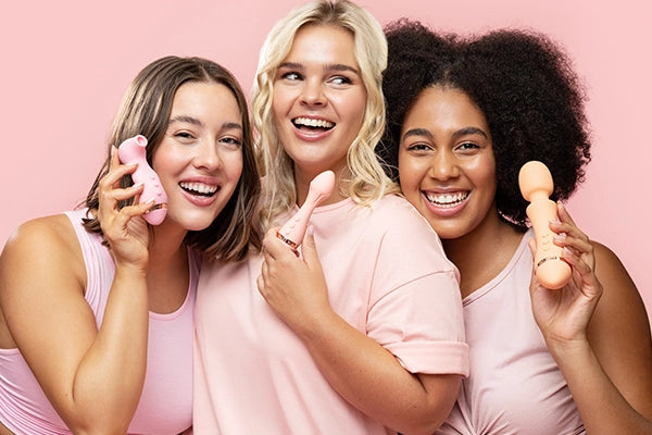 Three women holding VUSH vibrators (from left to right brunette holding Empress 2, blonde holding Rose 2, brunette holding Majesty 2)