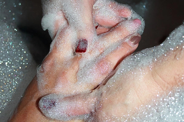 Soapy hands being washed in bath