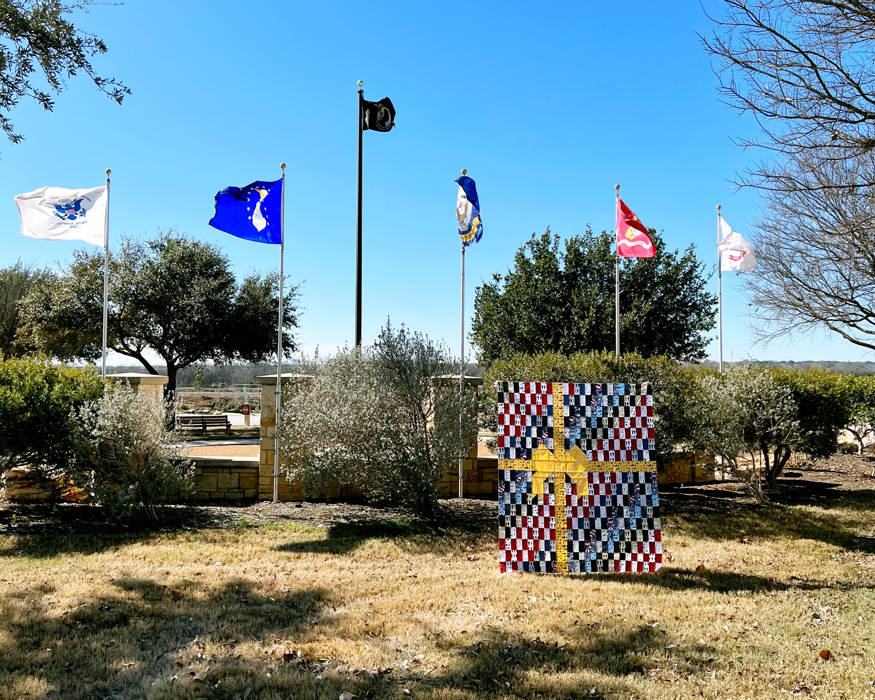 All Wrapped Up quilt in front of US Armed Forces flags blowing in the wind