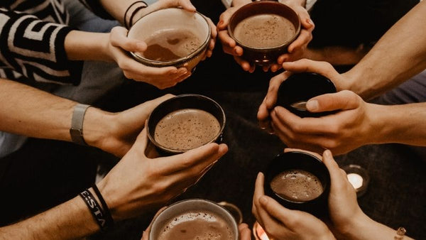Tassen voller Ritualkakao werden auf einer Kakaozeremonie in die Mitte gereicht, zum Teilen