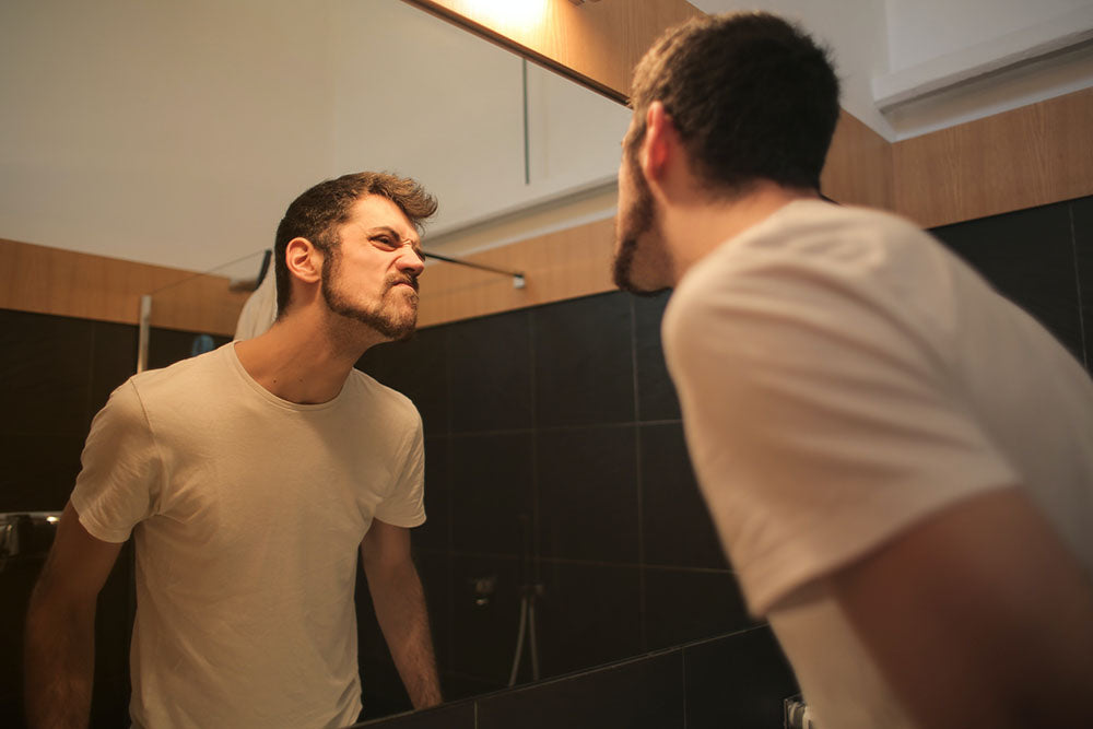 Man with beard checks his beard in the mirror