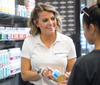 5 Star Nutrition employee in a while polo smiling at a customer as she hands over a supplement bottle