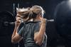 Woman athlete in motion lifting a barbell weight on her shoulders. 