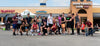 A large group of smiling athletes holding out five fingers in front of a 5 Star Nutrition storefront.