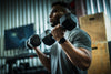 Close up of a male athlete in the gym doing bicep curls with heavy dumbbells