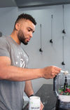 A man scooping a powdered supplement into his blender