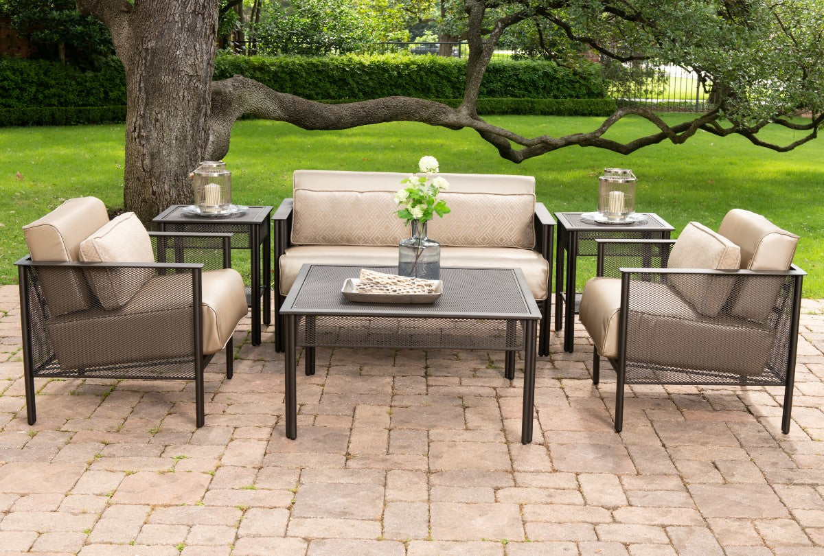 wrought iron mesh outdoor sofa set sitting under a tree on a brick patio