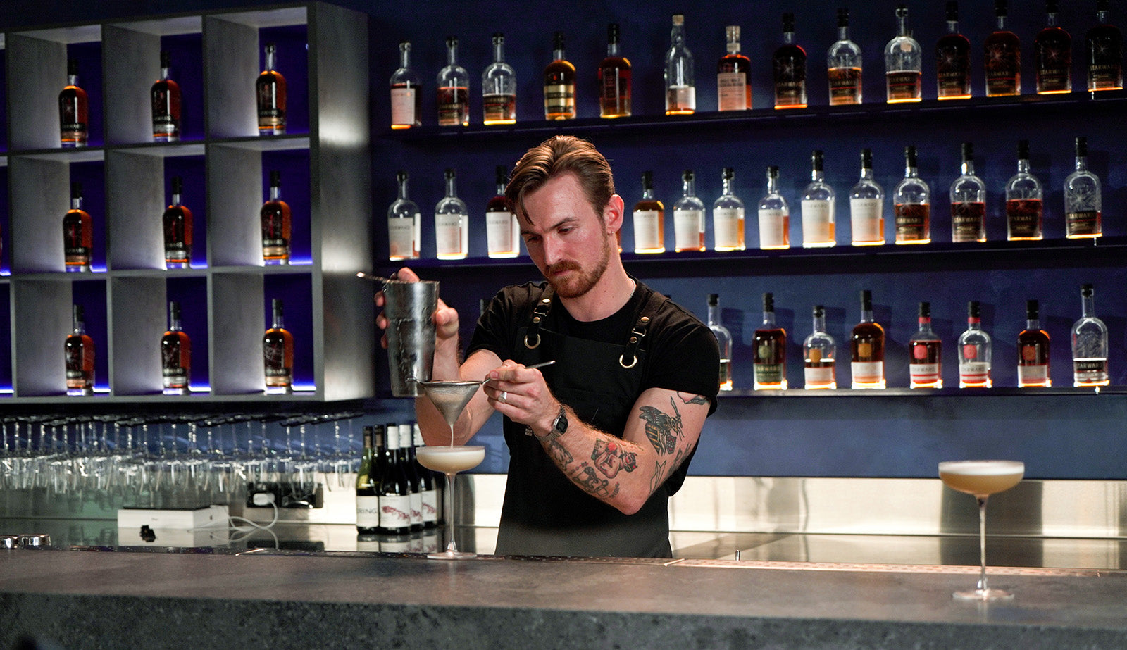 Starward bar and distillery a man shaking cocktails at a blue modern bar